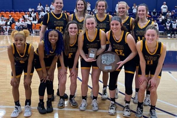 A group of women in uniforms holding a trophy